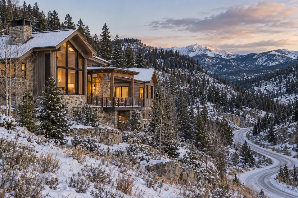 Foothills home among forested hillsides east of Bozeman with a winding canyon road and late autumn snow